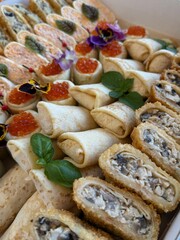 Served brunch with big very of snacks with stuffed crepes and tartlets with red caviar closeup. Celebration.  
