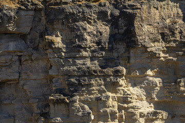 Fototapeta premium Rocky cliff formation showcasing layered textures and natural erosion in sunlight during midday hours