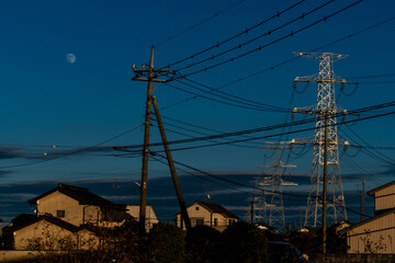 transmission steel tower carries high-voltage lines to the area at dusk in the Saitama countryside, Japan.
