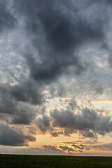 Dramatic sunset sky filled with clouds over a vast field at dusk capturing vibrant colors and natural beauty