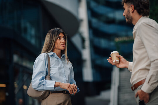 Business people talking during coffee break in front of modern office buildings