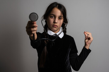 A girl with braids in a gothic style on a dark background with stethoscope.