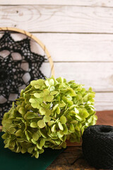 Autumn still life with crochet doily, pumpkin, dried hydrangea flowers, yarn, and pumpkin-shaped mug on rustic wooden surface. Warm cozy composition for handmade, home, or seasonal design.