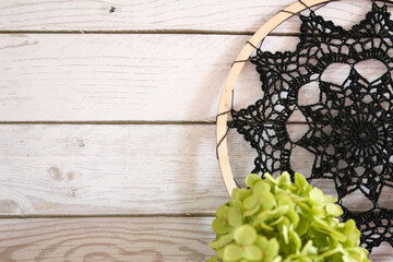 Autumn still life with crochet doily, pumpkin, dried hydrangea flowers, yarn, and pumpkin-shaped mug on rustic wooden surface. Warm cozy composition for handmade, home, or seasonal design.