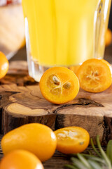 citrus-flavored orange juice and fresh kumquat fruits on a wooden table, delicious orange juice and fresh kumquat fruits next to a glass