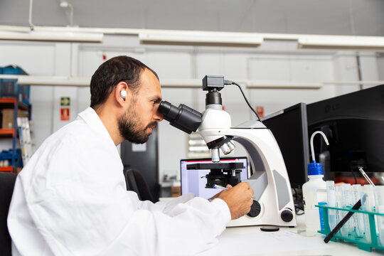 Scientist analyzing sample with optical microscope in modern laboratory