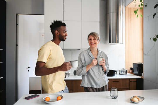 Couple enjoying coffee together and smiling in modern home kitchen