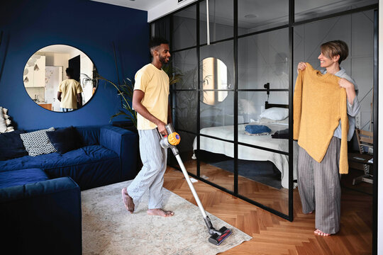 Couple cleaning and chatting in modern home living room during morning