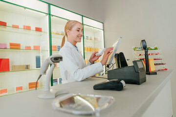 Pharmacist processing payment at pharmacy counter with medicines