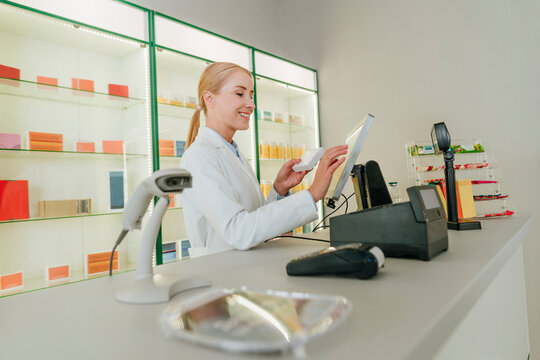 Pharmacist processing payment at pharmacy counter with medicines