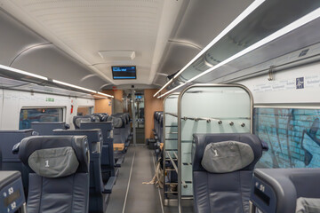 Fototapeta premium First class train quiet zone. First-class quiet zone with leather seats and luggage racks. Bright lighting creates a clean and calm atmosphere.