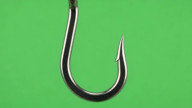 Close-up of a shiny metal fish hook against a green background.
