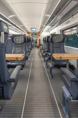 Obraz premium First-class seats with foldable wooden tables line both sides of the aisle. Modern, clean, and ready for travel.