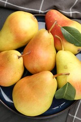Many fresh pears and leaves on black table, top view