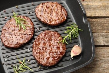 Pan with grilled patties and spices on wooden table, above view