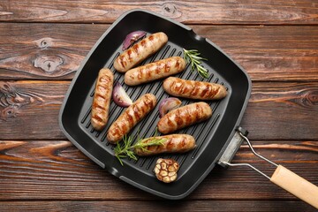 Pan with grilled sausages and spices on wooden table, top view