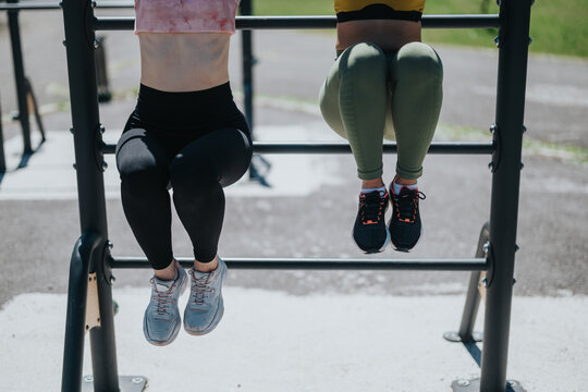 Two people working out on pull-up bars in a park, focusing on physical fitness.