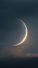 Obraz premium A crescent moon glows softly against a backdrop of dark, cloudy skies, creating a serene and mystical atmosphere.