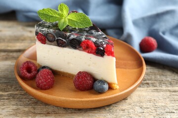 Piece of delicious cheesecake with berries and mint on wooden table, closeup