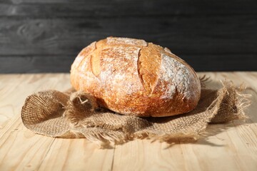Loaf of fresh bread on light wooden table, closeup