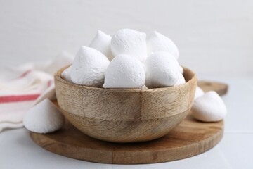 Delicious meringue cookies in bowl on white table, closeup