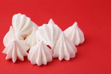Delicious meringue cookies on red background, closeup