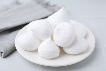 Delicious meringue cookies on white tiled table, closeup