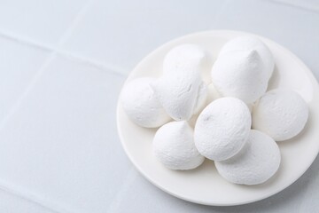 Delicious meringue cookies on white tiled table, closeup. Space for text