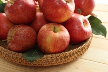 Fresh apples and green leaves on wooden table, closeup