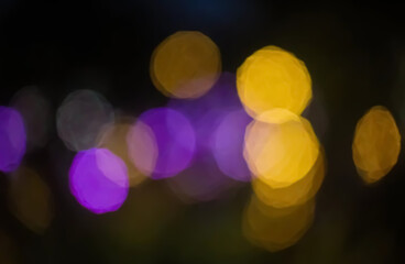 Golden and violet bokeh lights shimmer against the dark, creating a dreamy dance of warmth and wonder in the night.