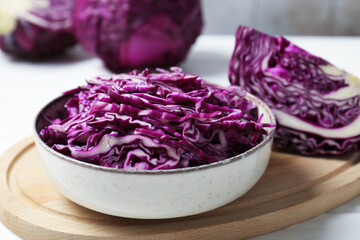 Fototapeta premium Shredded red cabbage in bowl on white wooden table, closeup