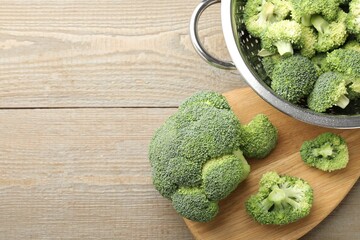 Fresh raw broccoli in colander on wooden table, top view. Space for text