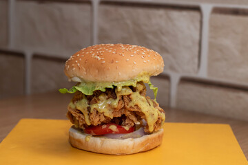 Crispy Fried Chicken Zinger Burger with Creamy Sauce, Lettuce, and Tomato on Yellow Board side view of junk food
