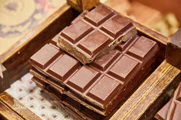 Stack of gourmet dark chocolate bars in a rustic wooden display.