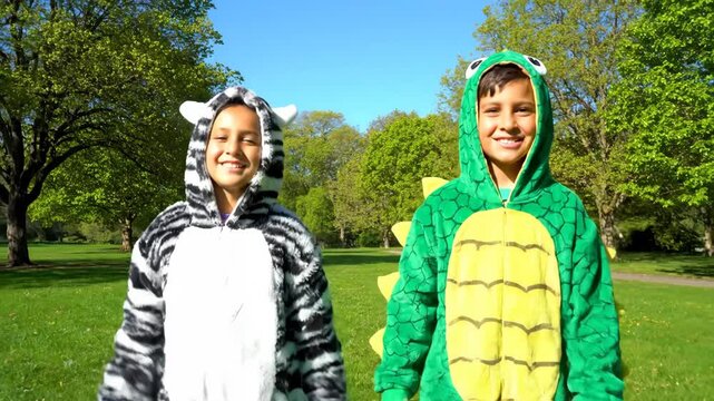 Happy Children in Animal Costumes Playing Outdoors - Two happy children, dressed in adorable zebra and dinosaur costumes, are playing in a sunny park.