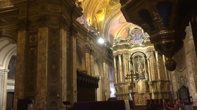 Warm yellow light illuminates the interior of the Buenos Aires Metropolitan Cathedral, revealing intricate details of the vaults and the main altar