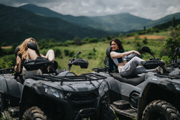 Young friends enjoying a fun ride on quad bikes, taking a break in a beautiful natural setting with mountains and lush greenery in the background.