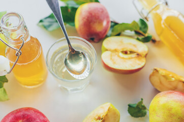 Apple cider vinegar against a background of apples. Selective focus.