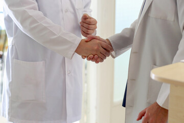 Close-up of two doctors shaking hands, favorable treatment prognosis. Medicine concept