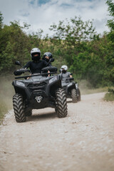 Group of friends enjoying an adventurous ride on quad bikes along a dirt path surrounded by scenic greenery. © qunica.com