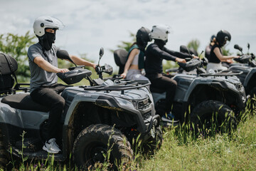 Friends enjoying an adventurous ride on quad bikes across a green trail, experiencing outdoor...