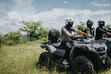 A group of friends wearing helmets and riding quad bikes on a scenic outdoor trail. © qunica.com