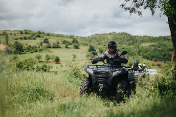 Friends enjoy an adventurous day riding quad bikes through scenic green meadows and hills,...
