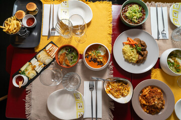 Top-down view of a restaurant table filled with diverse dishes and drinks, including salads, pasta, seafood, desserts, and wine, showcasing a vibrant feast.