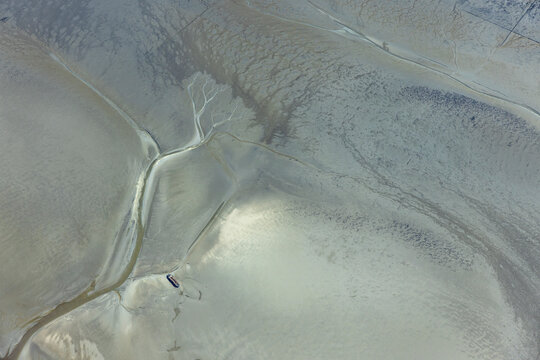 Aerial view of mud flats at low tide in the North Sea with stranded ship. Wadden Sea, Germany