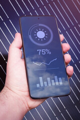 Hand with smartphone and solar station monitoring application. Wireless control and data of power plant.