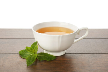 Aromatic tea in cup and mint on wooden table against white background