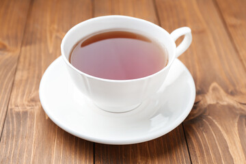 Cup of aromatic black tea on wooden table, closeup