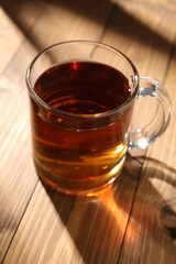 Aromatic black tea in cup on wooden table, closeup