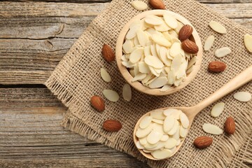 Fresh almond flakes and whole nuts on wooden table, flat lay. Space for text